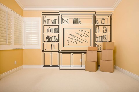 Moving boxes in empty room with shelf design drawing on the wall