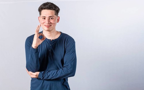 Smiling man showing ok gesture looking at camera