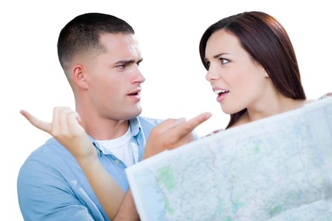 Young lost and confused military couple looking at map isolated on white