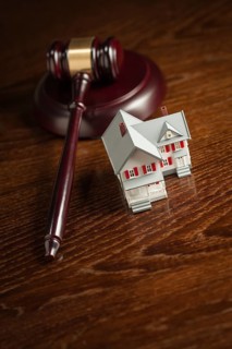 Gavel and small model house on wooden table