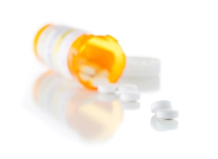 Non-Proprietary medicine prescription bottle and spilled pills isolated on a white background