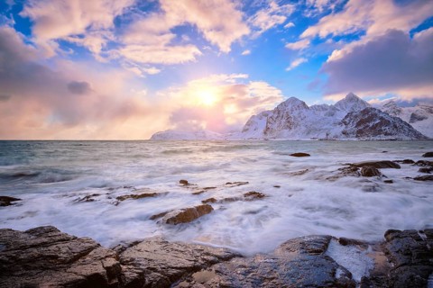 Beach of Norwegian sea on rocky coast in fjord on sunset in winter Vareid beach