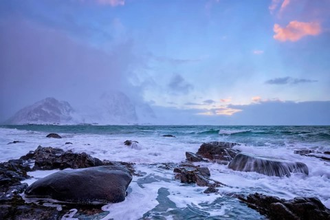 Beach of Norwegian sea on rocky coast in fjord on sunset in winter. Vareid beach