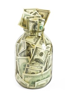 Glass jar full of hundreds of dollars isolated on white background