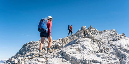 Hiker with climbing helmet on a steep rocky ridge