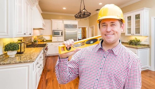 Smiling contractor with level wearing hard hat standing in custom kitchen