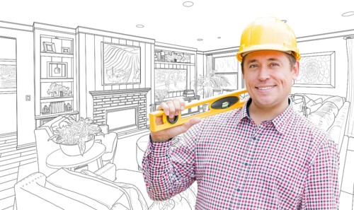 Smiling contractor in hard hat with level over custom living room drawing