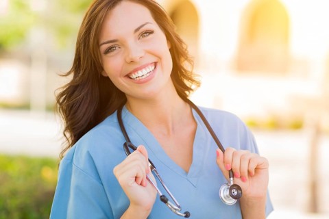 Portrait of young adult female doctor or nurse wearing scrubs and stethoscope outside