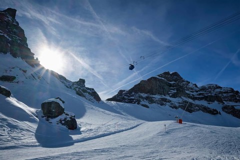 View of a ski resort piste with people skiing in Dolomites in Italy with cable car ski lift. Ski area Arabba. Arabba