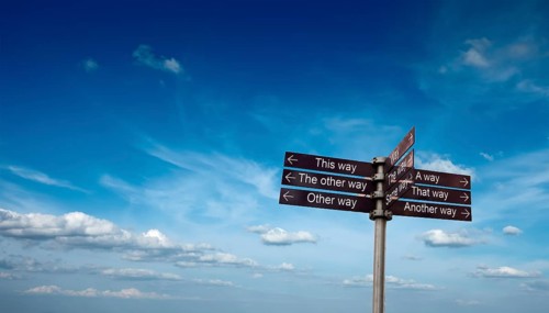 Signpost with directional signs in sky with clouds