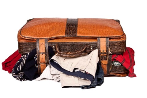 Overstuffed baggage in old suitcase isolated on white background
