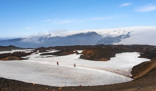 Two hikers on a hiking trail through a snow field