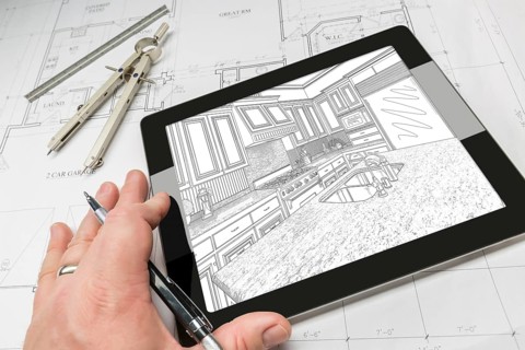 Hand of architect on computer tablet showing custom kitchen illustration over house plans