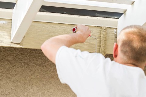 Professional painter using A small roller to paint house fascia