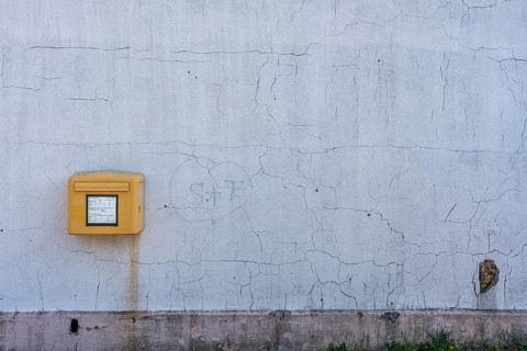 Yellow Deutsche Post letterbox on white wall