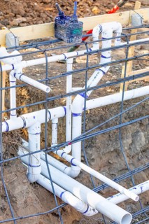 Newly installed PVC plumbing pipes and steel rebar configuration at construction site