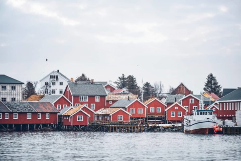 Reine fishing village on Lofoten islands with red rorbu houses in winter with snow with fishing boats. Norway