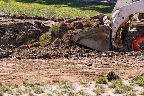 Small bulldozer digging in yard for pool installation
