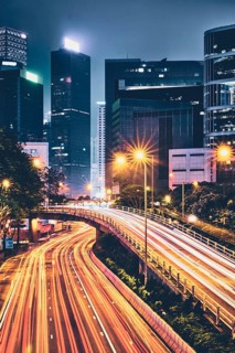 Street traffic in Hong Kong at night. Office skyscraper buildings and busy traffic on highway road with blurred cars light trails. Hong Kong