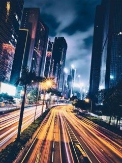Street traffic in Hong Kong at night. Office skyscraper buildings and busy traffic on highway road with blurred cars light trails. Hong Kong