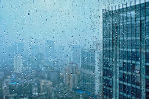 Rain water drops droplets on window glass texture with skyscrapers in background