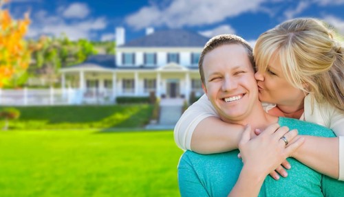 Happy couple hugging in front of a beautiful house