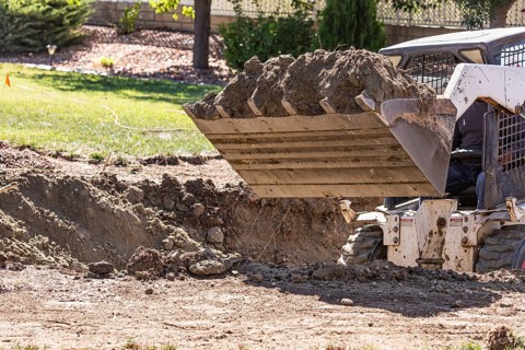 Small bulldozer digging in yard for pool installation