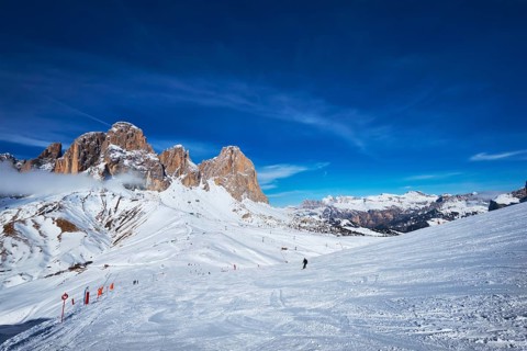 View of a ski resort piste with people skiing in Dolomites in Italy
