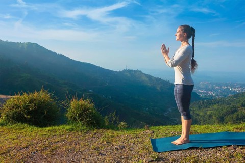 Woman doing Ashtanga Vinyasa Yoga asana Tadasana Samasthiti yoga posture in mountains in the morning