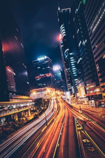 Street traffic in Hong Kong at night. Office skyscraper buildings and busy traffic on highway road with blurred cars light trails. Hong Kong