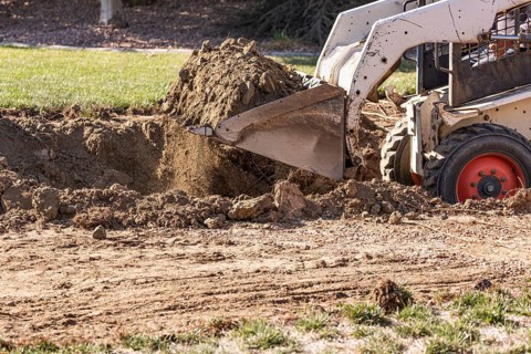 Small bulldozer digging in yard for pool installation