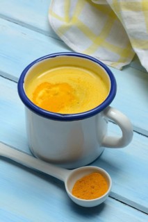 Kurkuma-Milch in Tasse und Kurkumapulver