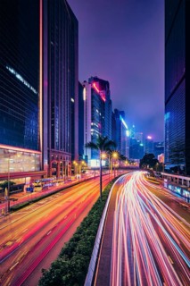 Street traffic in Hong Kong at night. Office skyscraper buildings and busy traffic on highway road with blurred cars light trails. Hong Kong