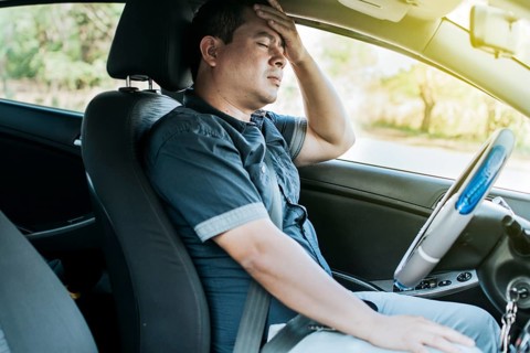 A person in his car with a headache