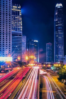 Street traffic in Hong Kong at night. Office skyscraper buildings and busy traffic on highway road with blurred cars light trails. Hong Kong