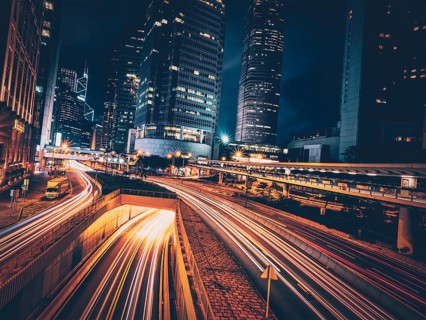 Street traffic in Hong Kong at night. Office skyscraper buildings and busy traffic on highway road with blurred cars light trails. Hong Kong
