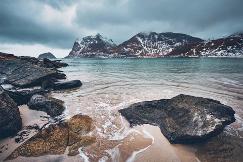Rocky coast of fjord of Norwegian sea in winter with snow. Haukland beach