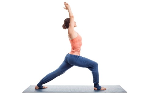 Beautiful sporty fit yogini woman practices yoga asana Virabhadrasana 1