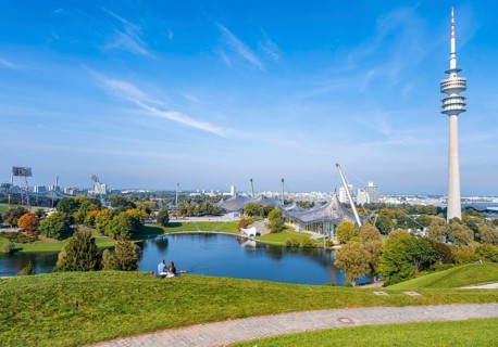 Two people sitting in the park with Olympic lake and Olympic tower