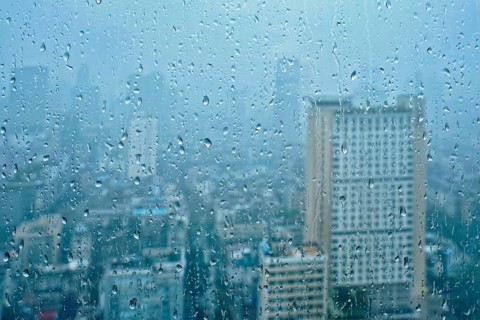 Rain water drops droplets on window glass texture with skyscrapers in background