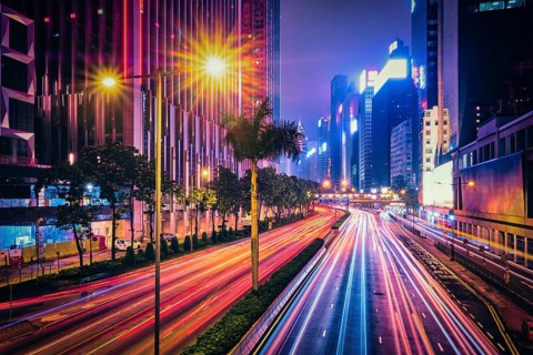 Street traffic in Hong Kong at night. Office skyscraper buildings and busy traffic on highway road with blurred cars light trails. Hong Kong