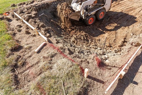 Small bulldozer digging in yard for pool installation