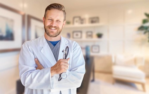Handsome young adult male doctor with beard inside office