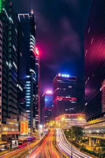 Street traffic in Hong Kong at night. Office skyscraper buildings and busy traffic on highway road with blurred cars light trails. Hong Kong