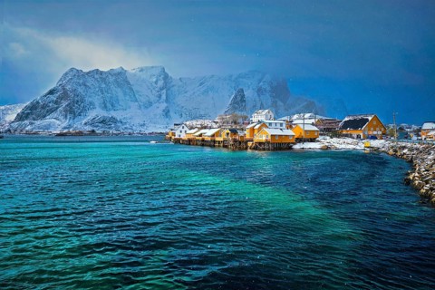 Yellow rorbu houses of Sakrisoy fishing village with snow in winter. Lofoten islands