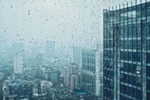 Rain water drops droplets on window glass texture with skyscrapers in background