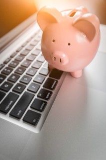 Piggy bank resting on laptop computer keyboard