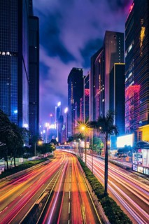 Street traffic in Hong Kong at night. Office skyscraper buildings and busy traffic on highway road with blurred cars light trails. Hong Kong