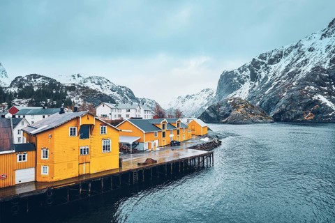 Panorama of Nusfjord authentic fishing village with yellow rorbu houses in Norwegian fjord in winter. Lofoten islands