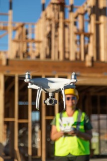Female pilot flies drone quadcopter inspecting construction site